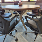 İstanbul Ofis Mobilya modern ahşap tablalı ve metal ayaklı yuvarlak ofis toplantı masası ve siyah çalışma sandalyeleri.